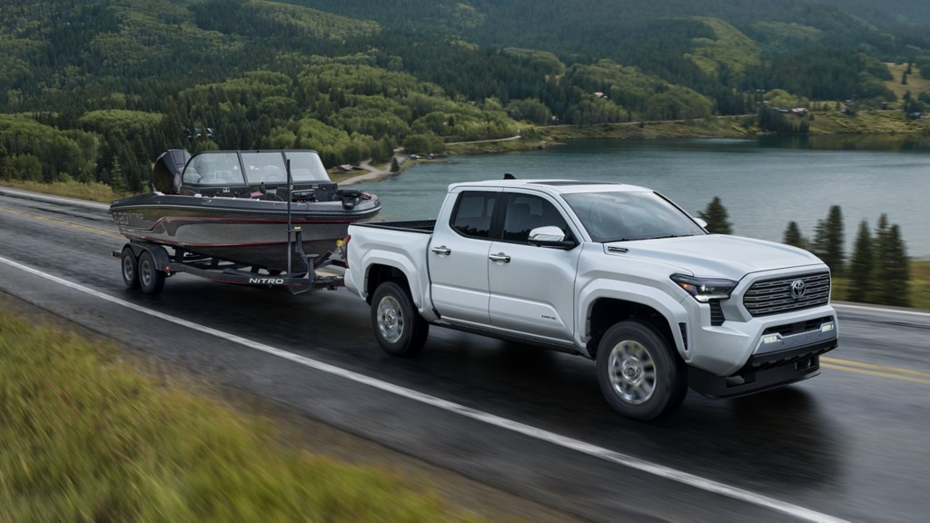 2025 Toyota Tacoma White Tacoma pulling speedboat on trailer next to a lake