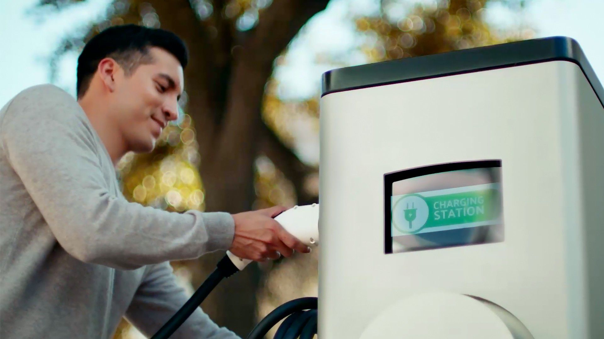 Image of man plugging his vehicle into a charging station.