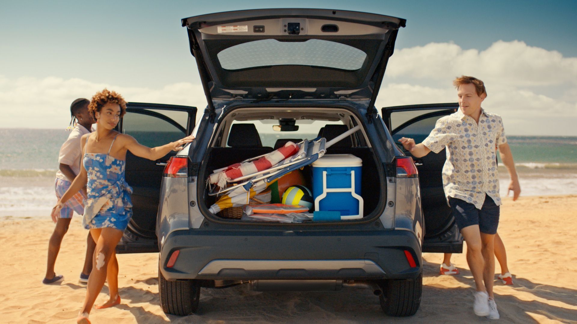 Family on beach grabbing gear from the back of a Toyota.