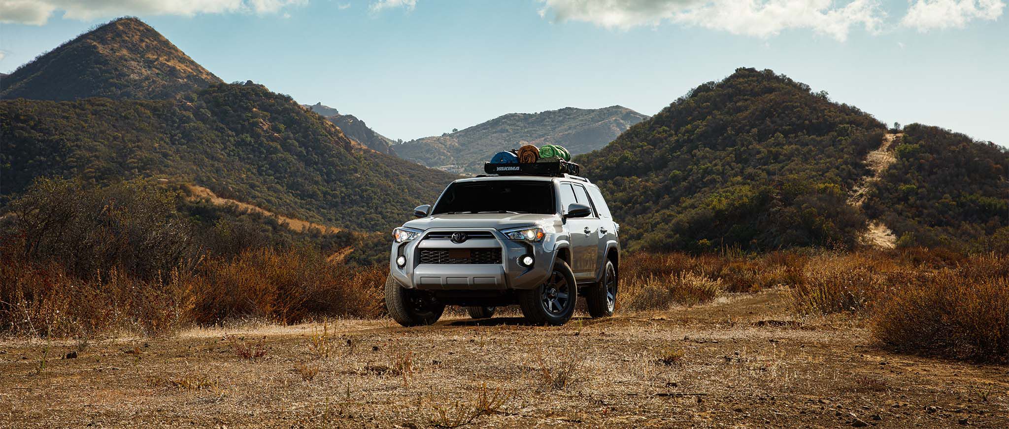 Una Toyota 4Runner plateada estacionada frente a montañas.