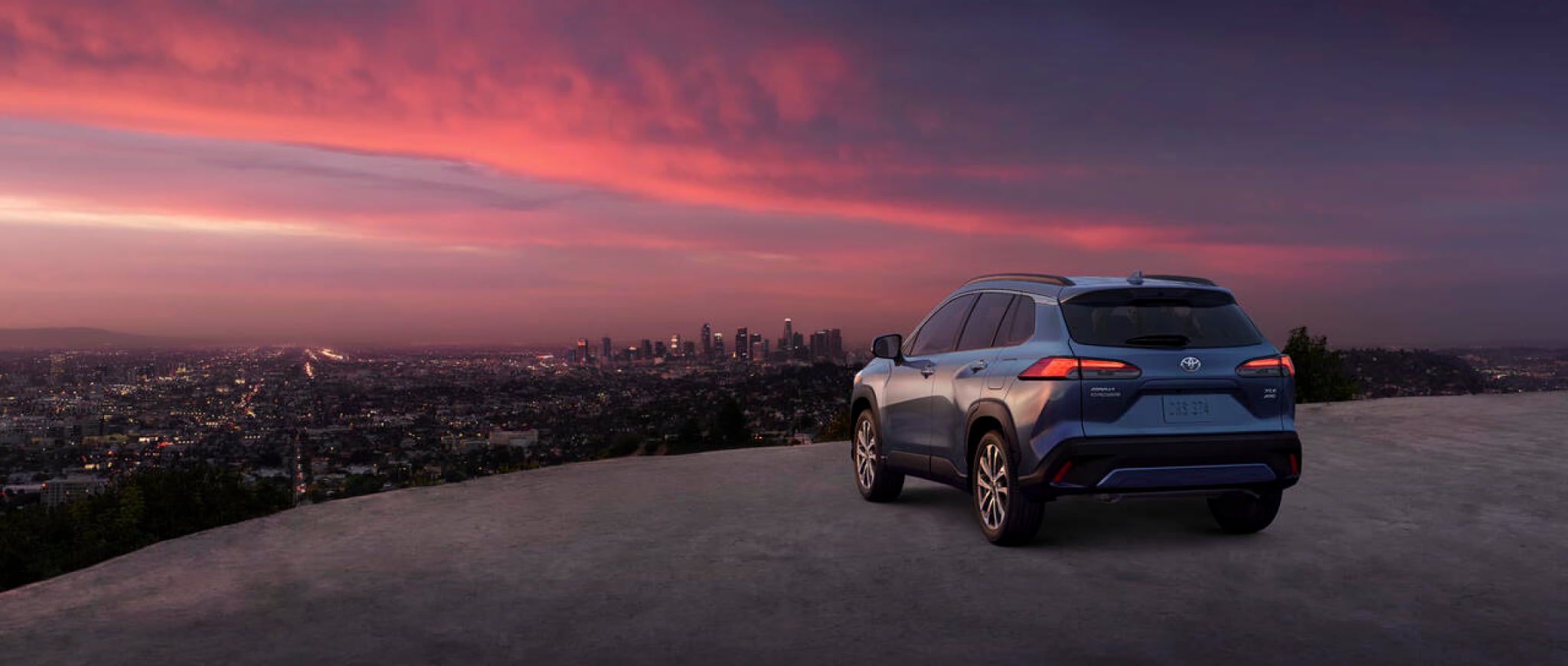 A 2022 Toyota Corolla Cross parked high above a city as sunset.