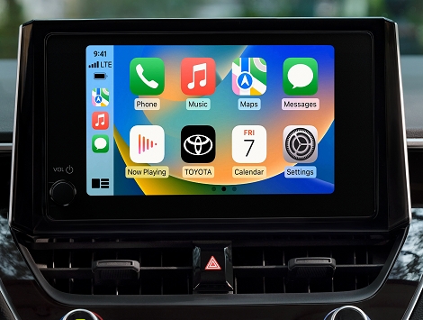 Se muestra la pantalla de 8.0 pulgadas del Toyota Corolla 2023 con varias opciones de menú y la aplicación Toyota en la pantalla contra un fondo verde borroso. 