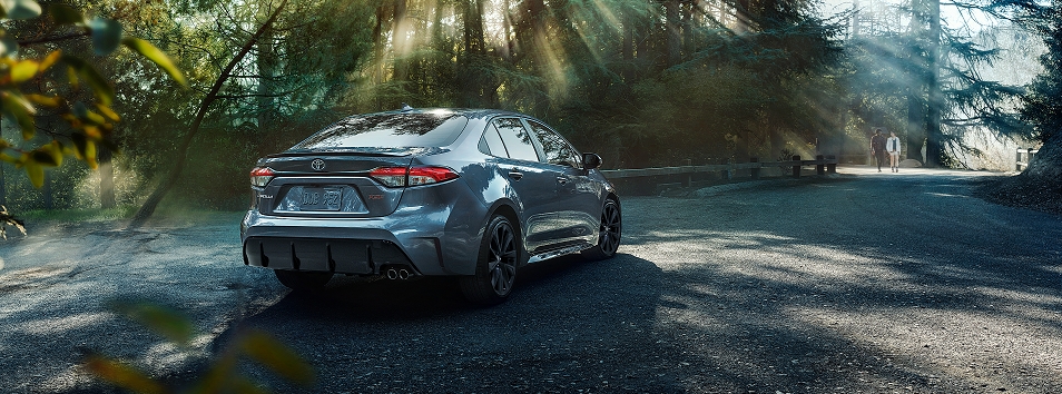 2023 Toyota Corolla XSE shown in Celestite parked on a gravel road in a lush forest.