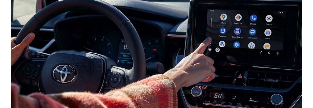 A driver interacts with the touch screen in a 2023 Corolla.
