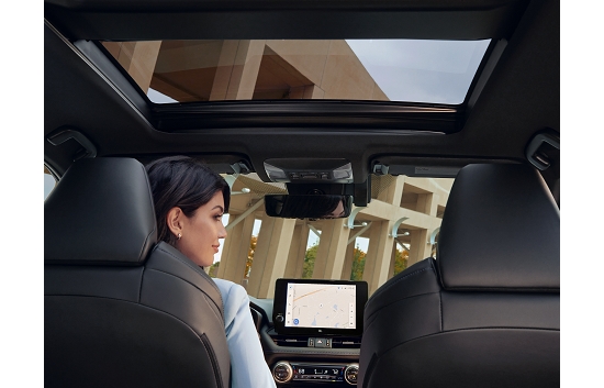 A woman seated in the driver's seat of a 2023 Toyota Cross with the sunroof open.