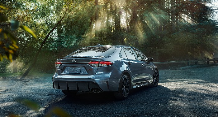 2023 Toyota Corolla XSE shown in Celestite parked on a gravel road in a lush forest.