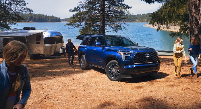 A 2023 Toyota Sequoia in the color Blueprint at a lakeside camping spot.