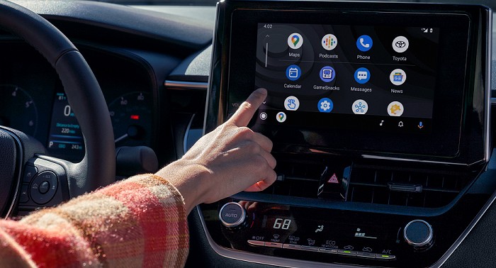 Una vista interior del Toyota Corolla 2023. El conductor tiene la mano izquierda en el volante mientras que la mano derecha interactúa con las opciones de navegación y de infoentretenimiento que se muestran en la pantalla.