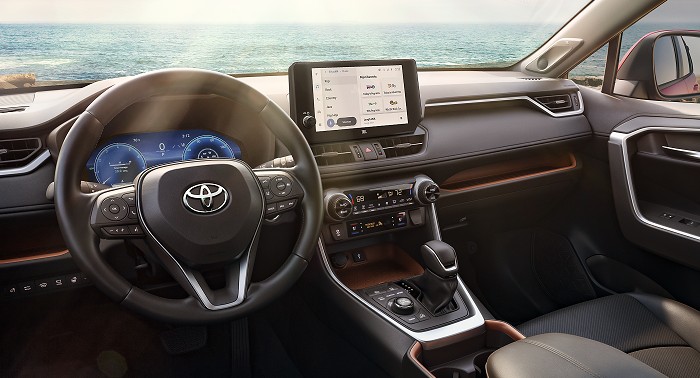 La vista interior de una Toyota RAV4 muestra su volante, conjunto de indicadores, tablero, palanca de cambios y pantalla táctil multimedia.