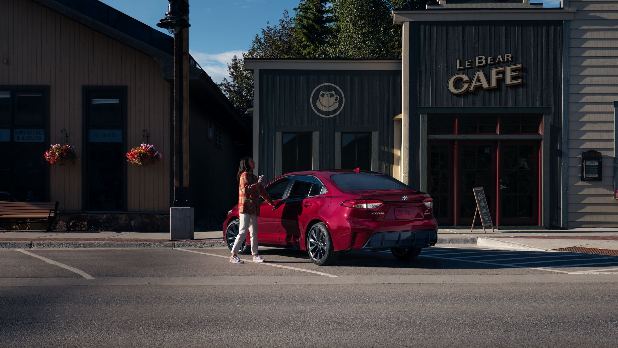 Hybrid SE AWD shown in Ruby Flare Pearl next to a coffee shop