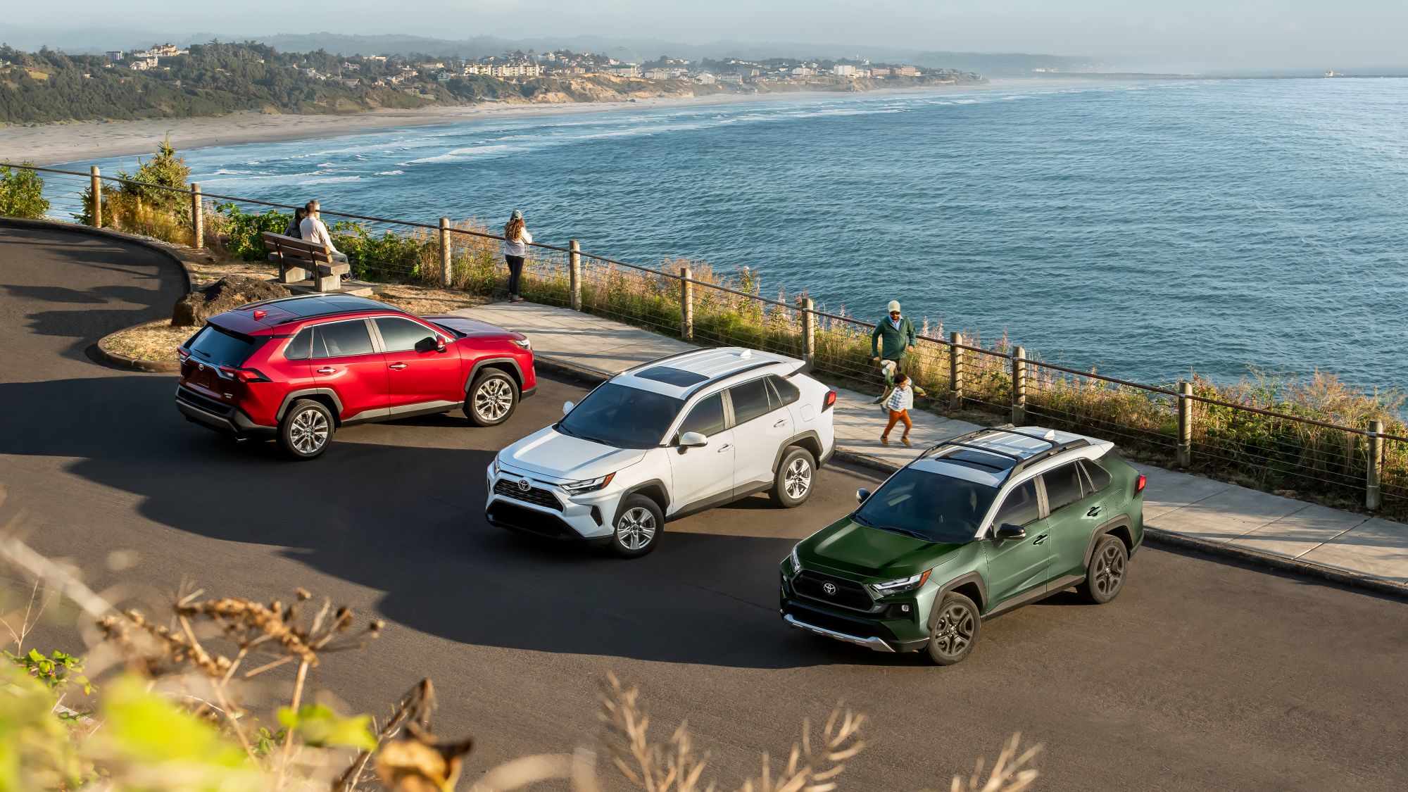 Ruby Flare Pearl, Ice cap white, and Army Green with Ice edge panoramic glass roof RAV4's parked parallel at a beach parking lot 