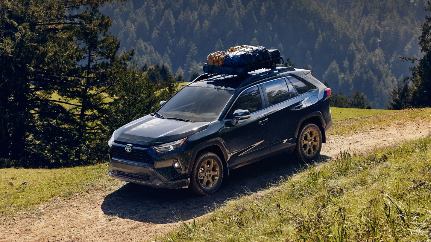 New 2024 Toyota RAV 4 with bronze wheels and camping roof rack driving into camp site