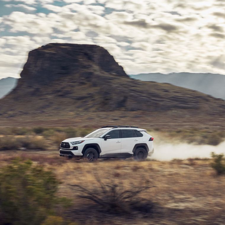 a white rav4 driving on a dirt road