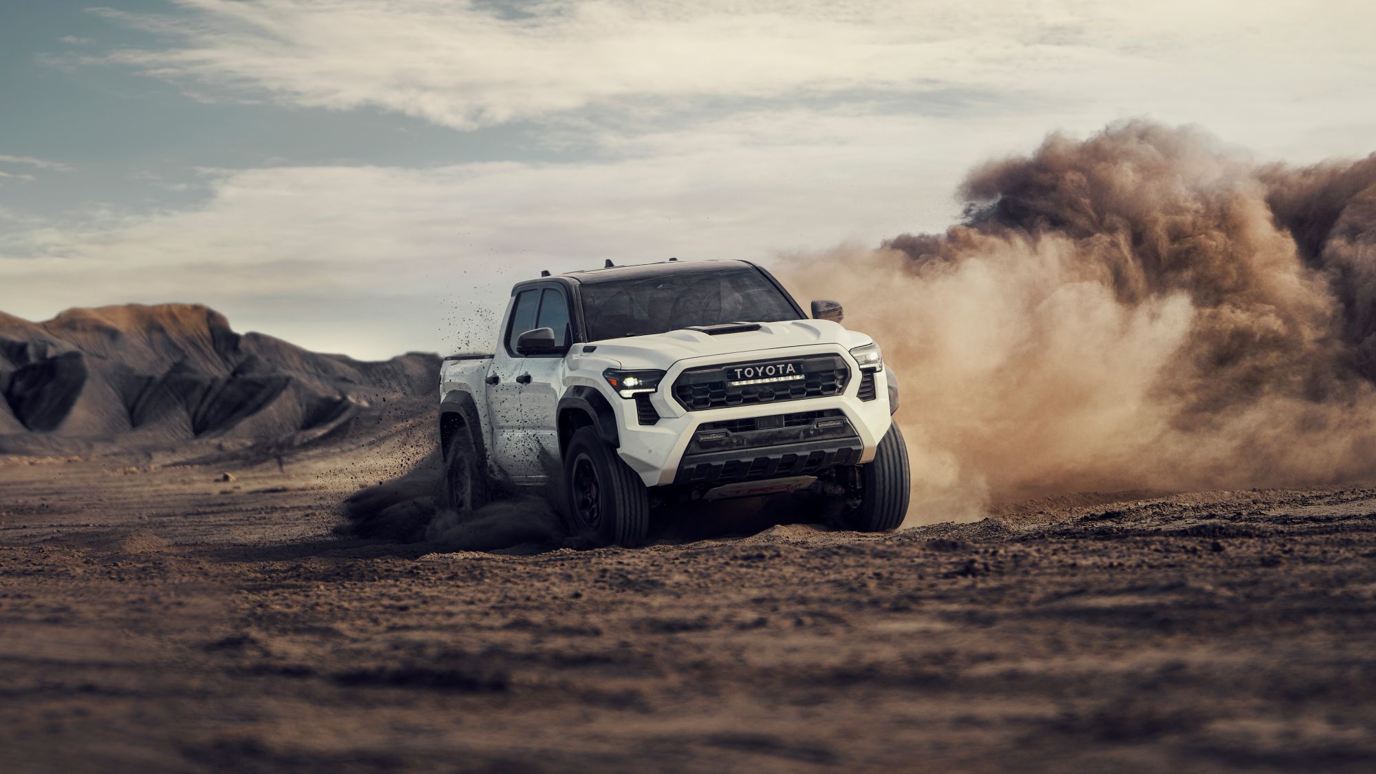2024 Toyota TRD Pro Tacoma shown in Ice Cap with Black roof driftin over sand dunes