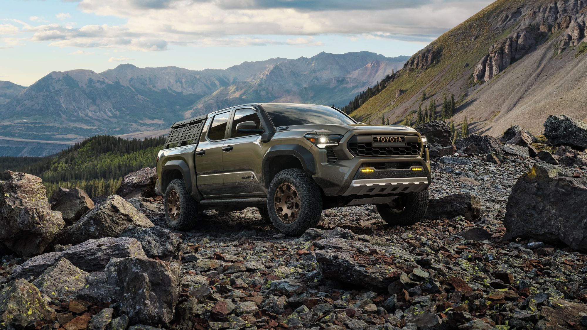 2024 Toyota Trailhunter shown in Bronze Oxide Tacoma parked on rocky mountain