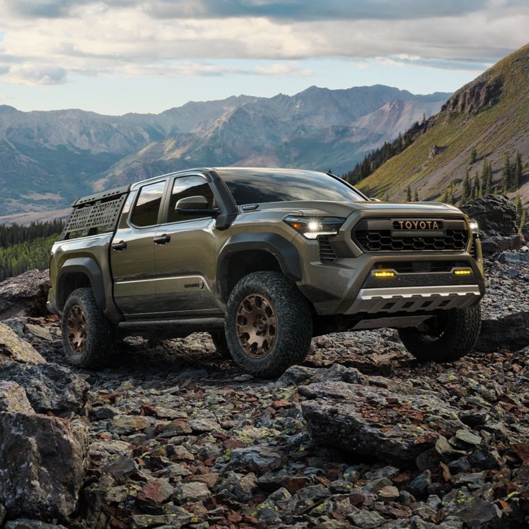 a green truck parked on a rocky trail