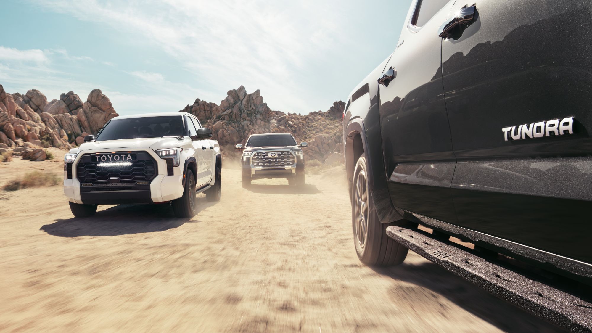 2024 white CrewMAx, TRD Pro, and black 1794 Edition CrewMax Toyota Tundra's drving in unisen towards camera view