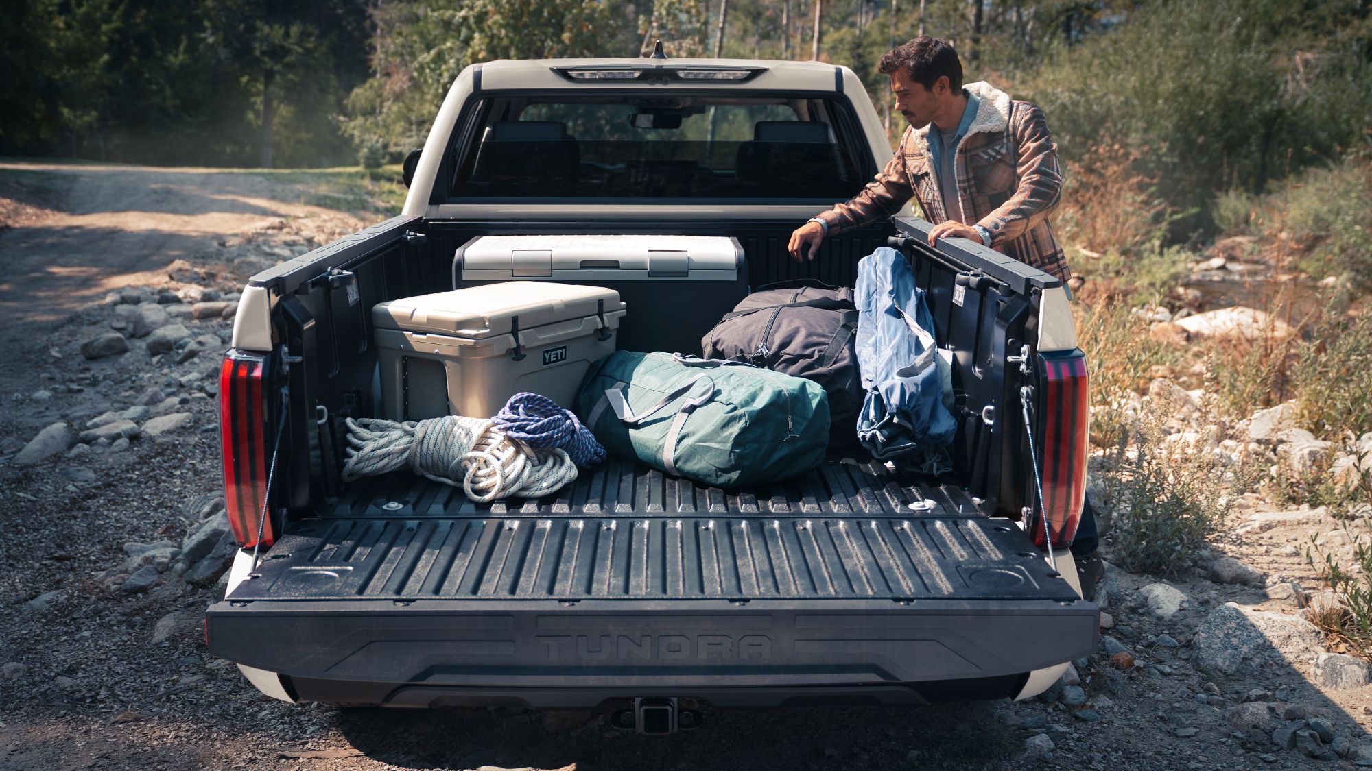camping gear in the back of a white truck in the woods. 