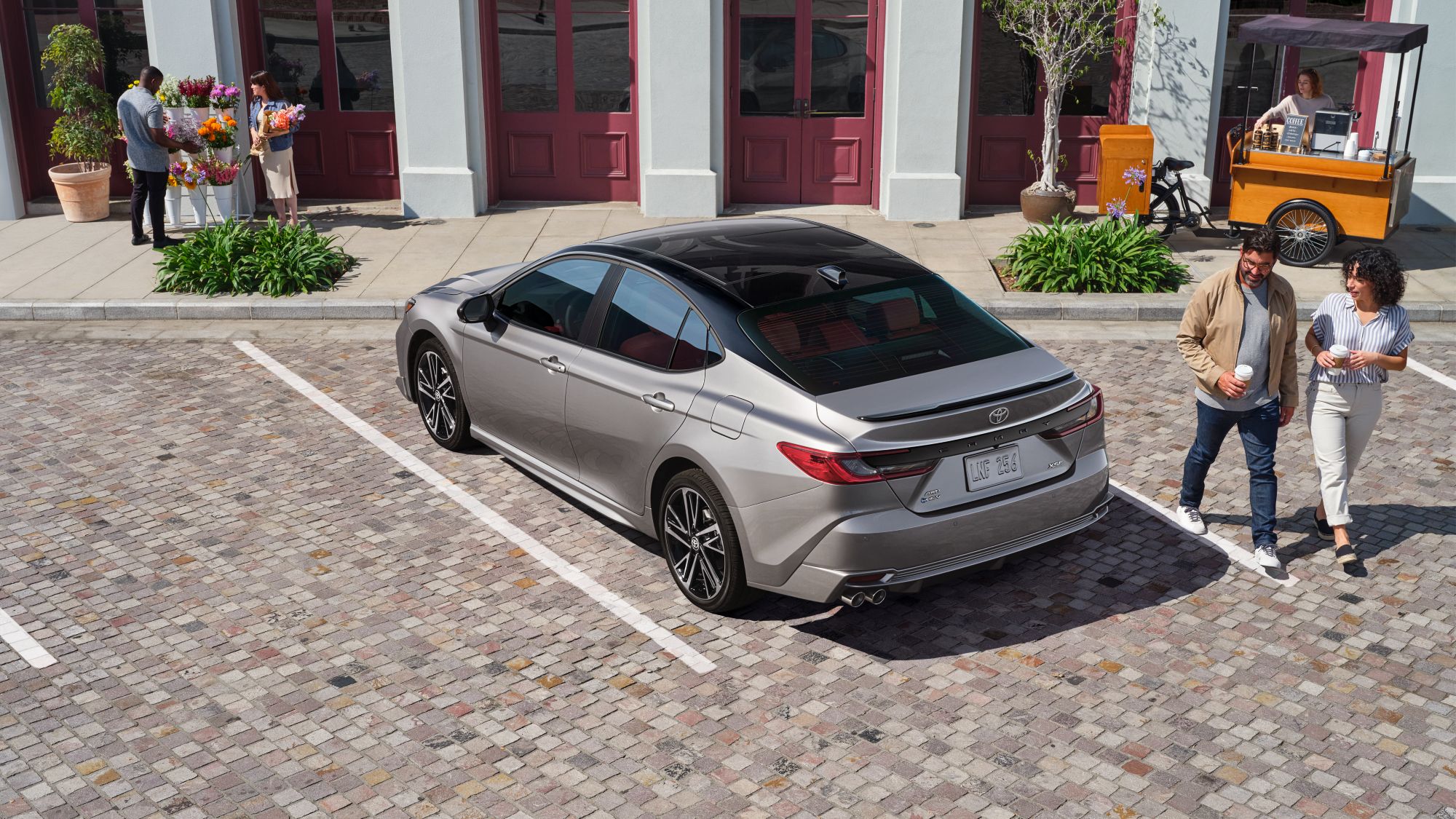 Tan Camry parked in front of store with people walking by