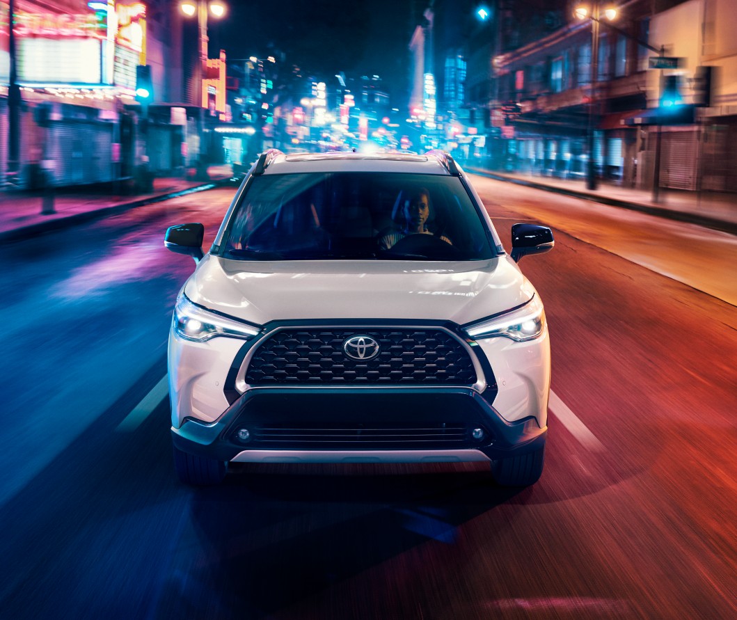 Corolla Cross front end view in nightlit cityscape