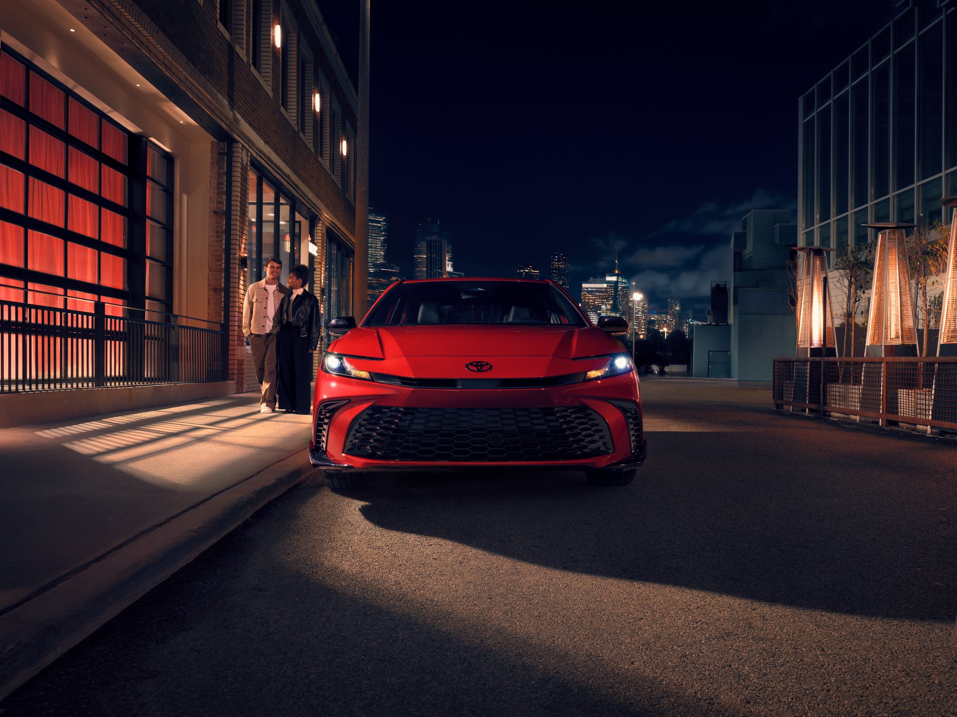 Front view of a red 2026 Toyota Camry on a city street at night