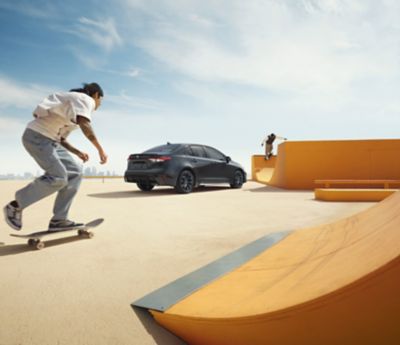 Skateboarder passing a Toyota Corolla