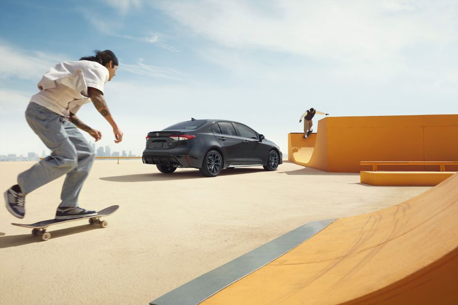 Skateboarder passing a Toyota Corolla