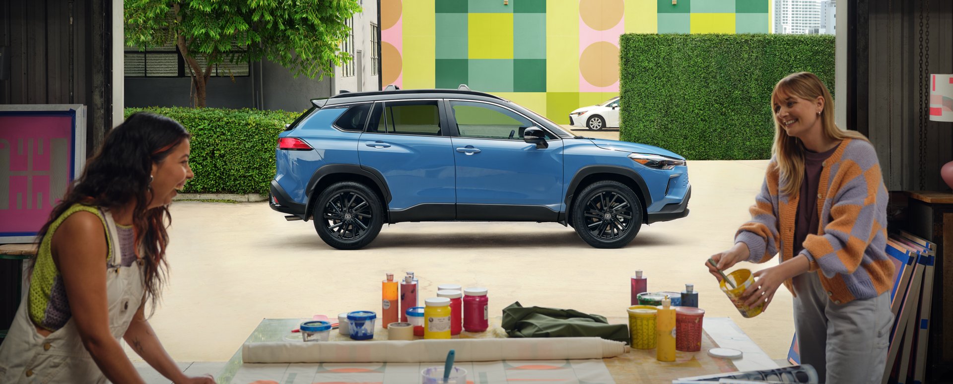 Illustrative: a blue 2026 Toyota Corolla Cross subcompact SUV behind two people at a table