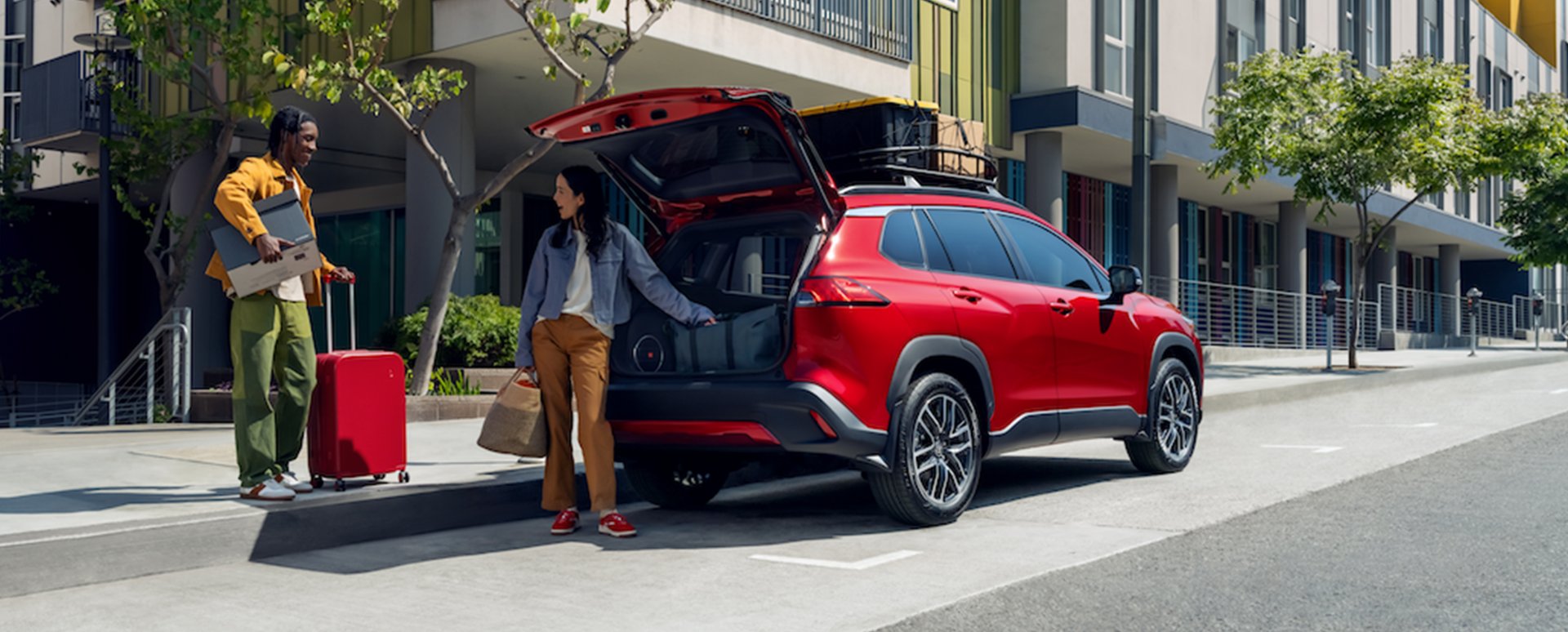 Illustrative: a red Toyota Corolla Cross with its liftgate open on a city street