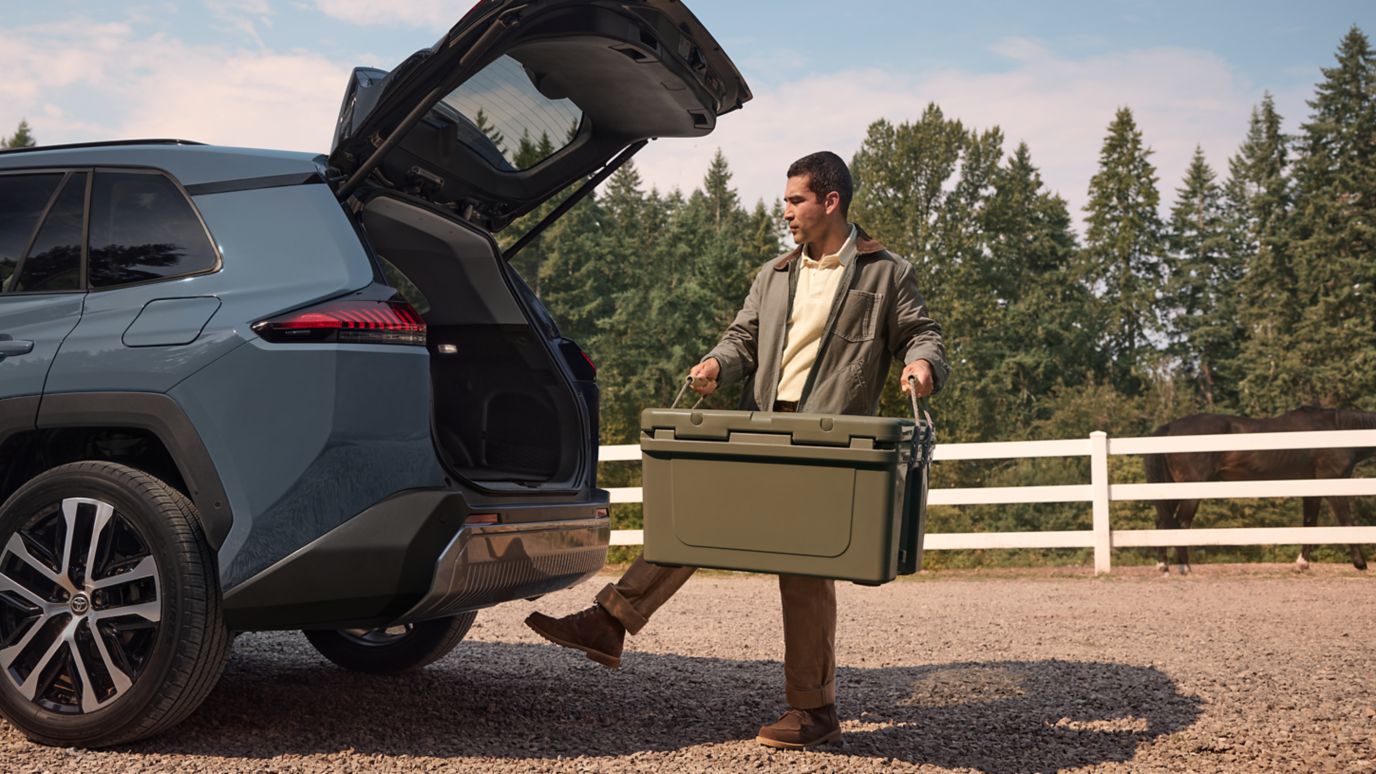 2026 Toyota RAV4 with its liftgate open as a camper loads a cooler, rear three-quarter view