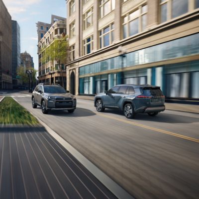 Official Toyota image showing two 2026 Toyota RAV4 variants driving through a city