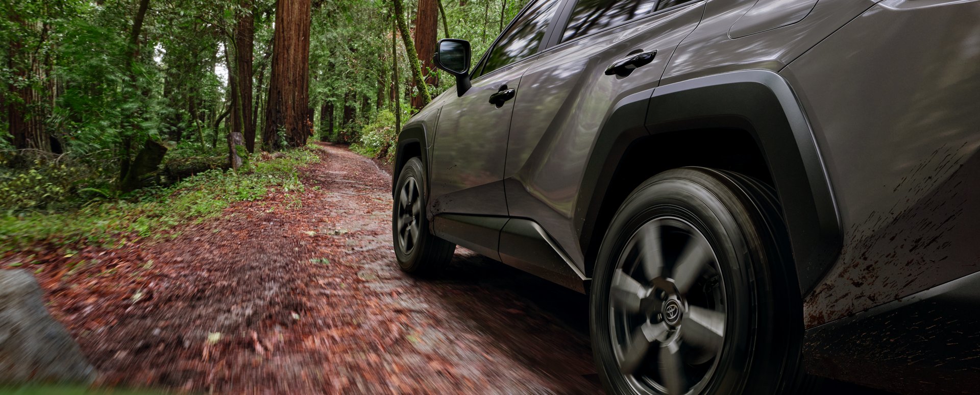 Front wheel and fender of a gray RAV4 Plug-in Hybrid on a forest trail