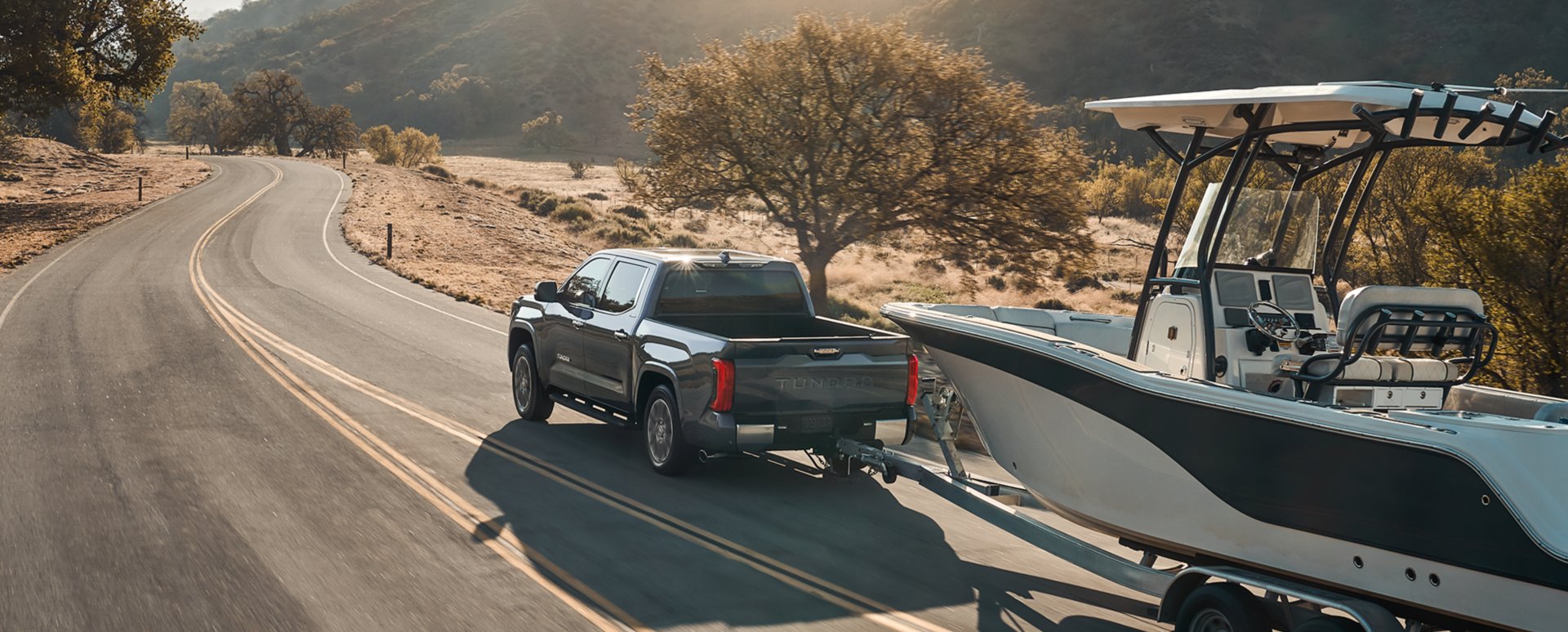 Illustrative: a Toyota Tundra full-size pickup towing a boat on a two-lane road